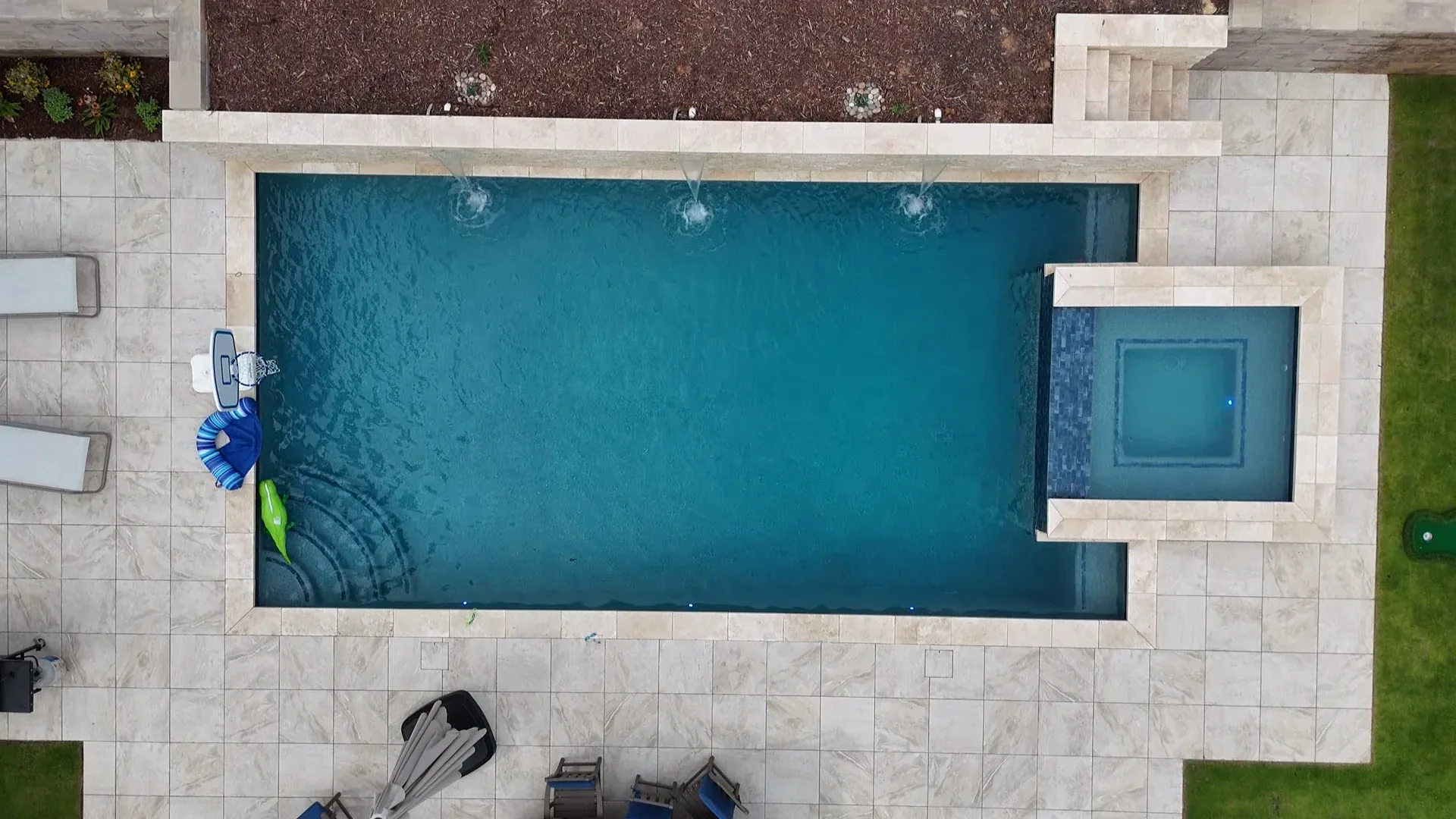 Drone view of a finished pool with a basketball hoop and pool floats, built for family play