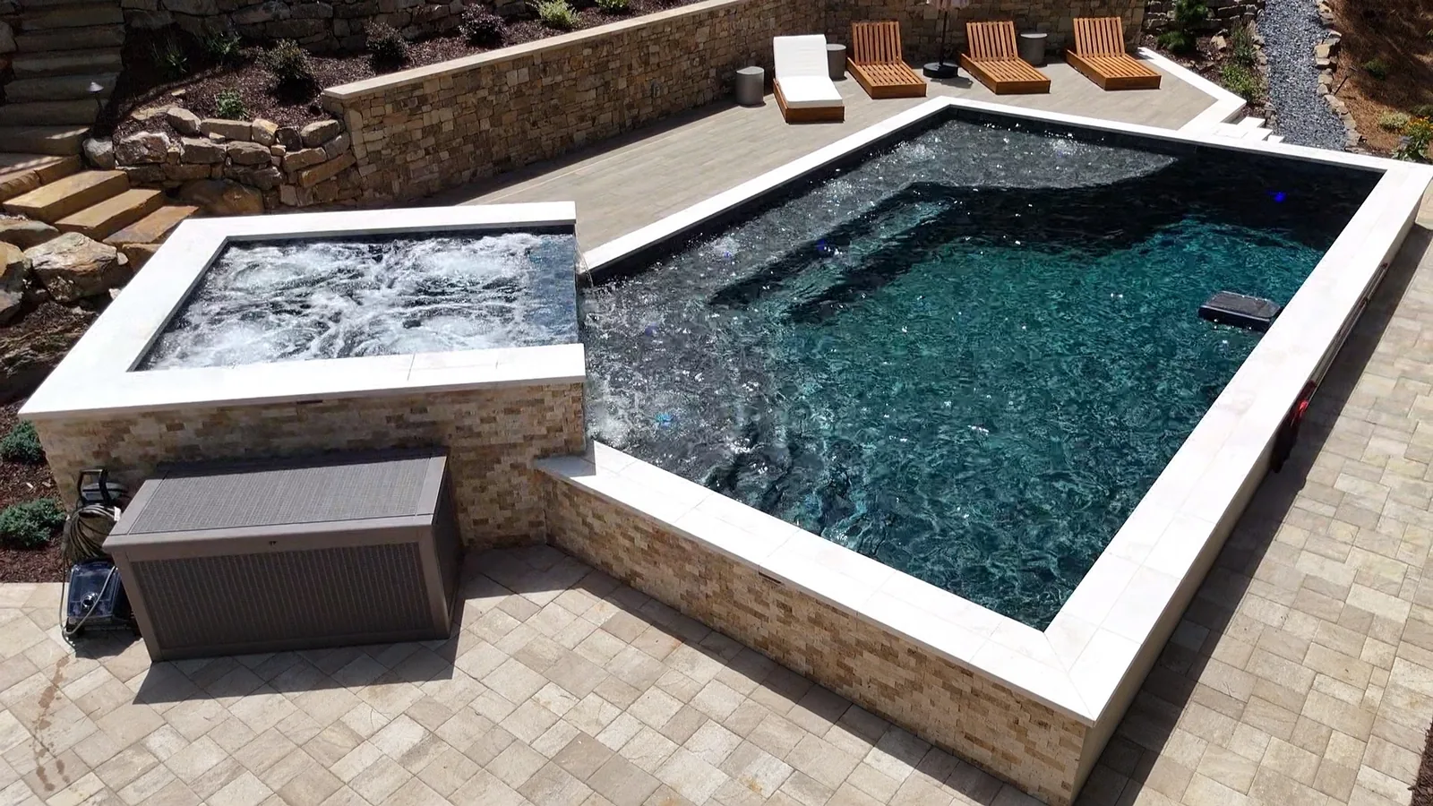 Raised spa spillover and pool seen from the lounge-chair deck beside it