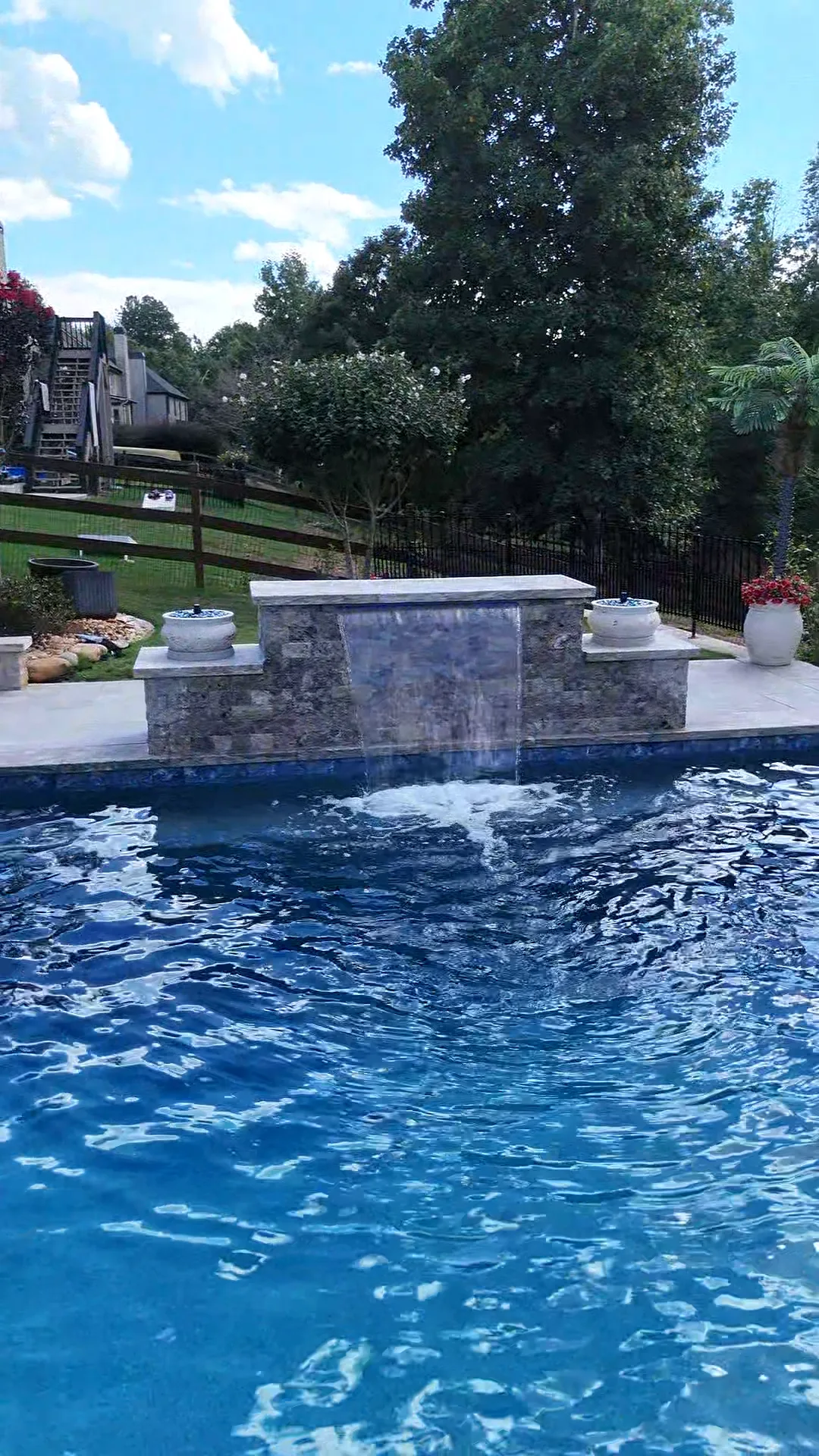 Waterfall flowing from a stone-faced wall into the blue Dallas pool