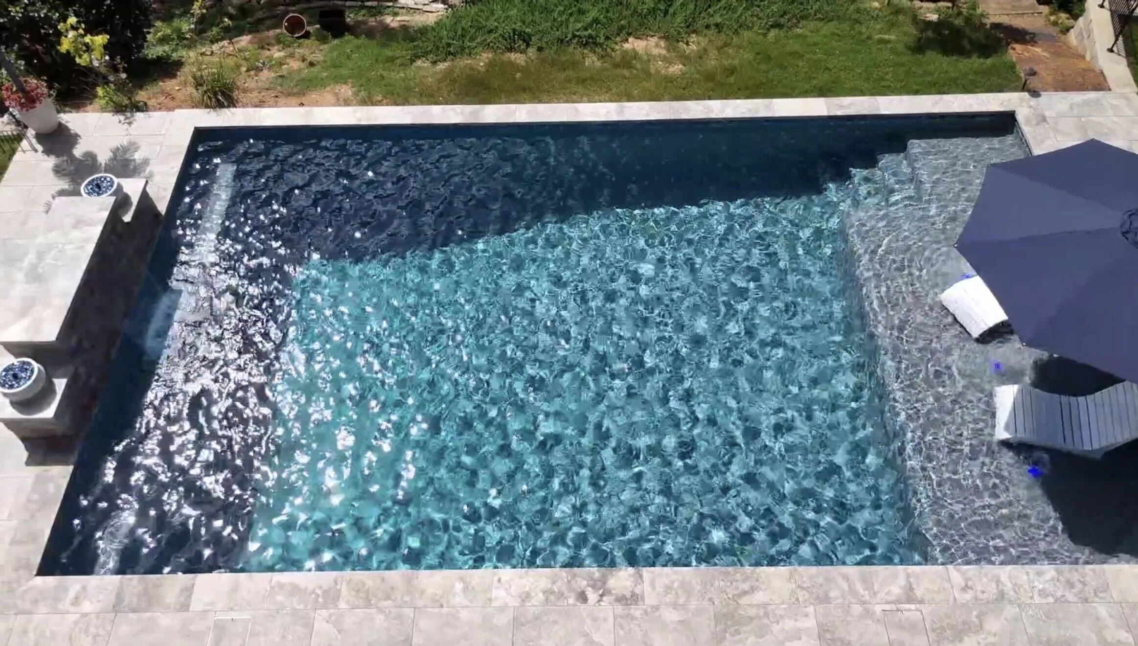 Wide view of a finished RutherfordMade pool in Dallas, Georgia, with a waterfall wall and two in-water loungers