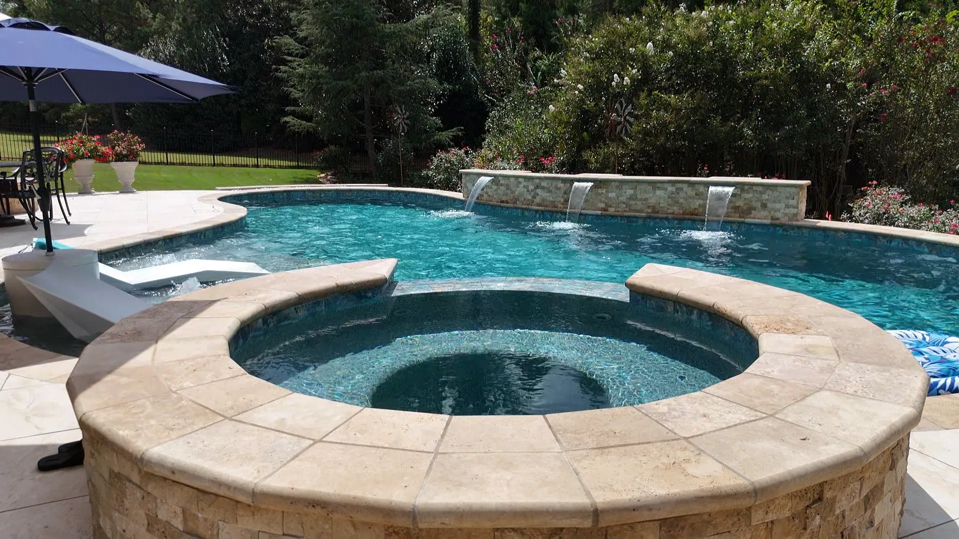 Round raised spa in front of the completed Curtis pool with in-water loungers and two water features