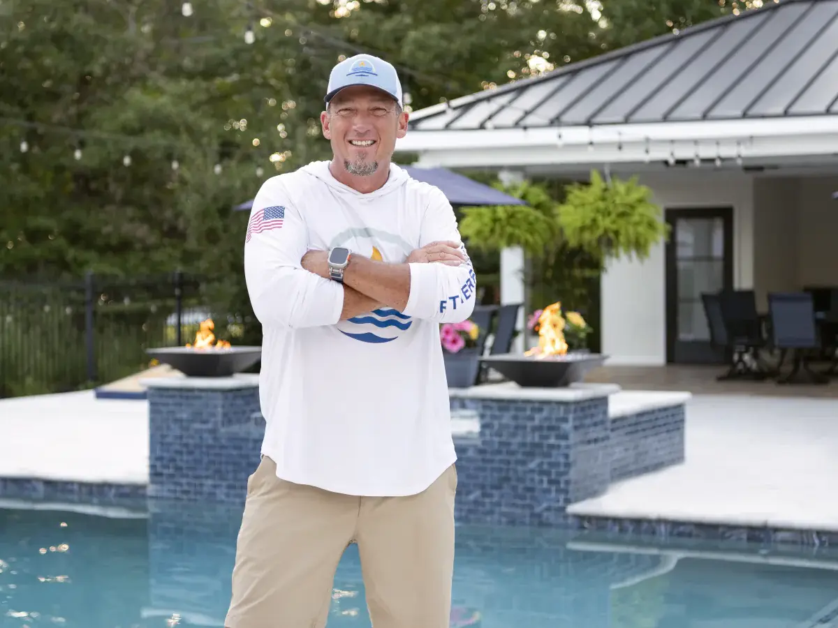 Scott Rutherford standing in front of a completed RutherfordMade pool with fire bowls and cabana