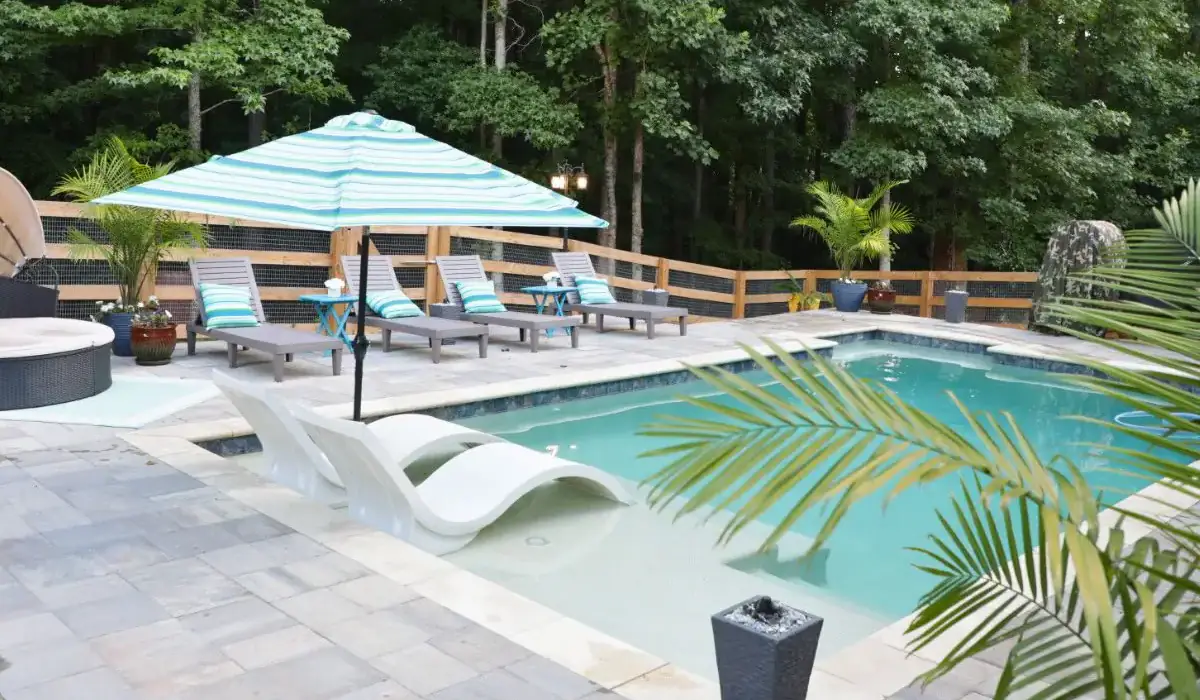RutherfordMade backyard with pool, integrated outdoor living, lounge chairs, and palm trees