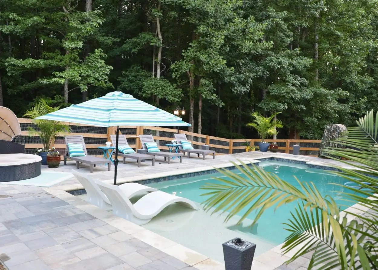 RutherfordMade resort-style pool with umbrellas, lounge chairs, and palm trees